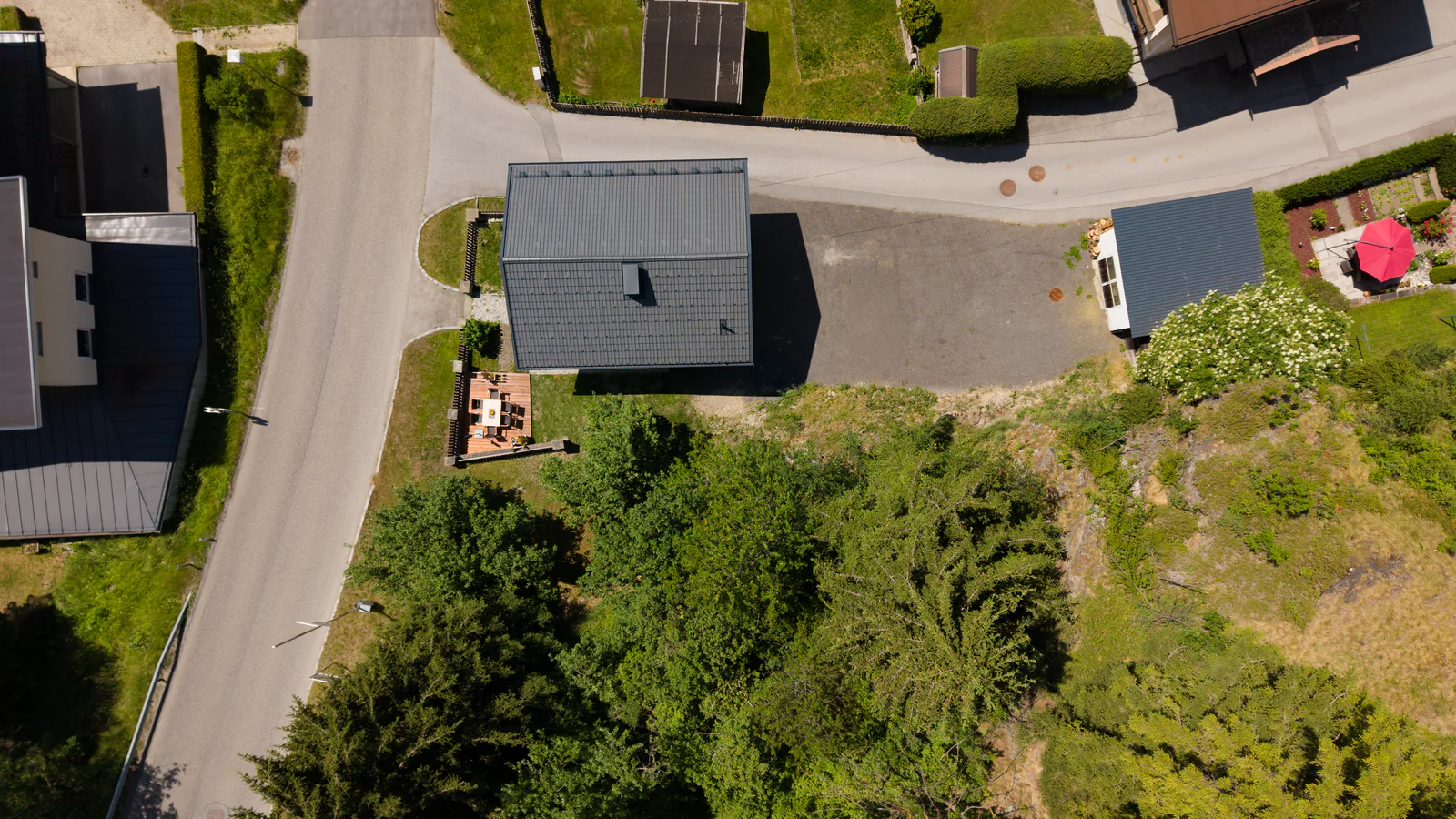Irmas Ferienhäusl von oben: das Haus mit dunklem Dach, links die Holzterrasse im Garten, rechts der Parkplatz
