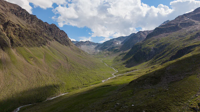 Grünes Hochtal mit gewundenem Gebirgsbach